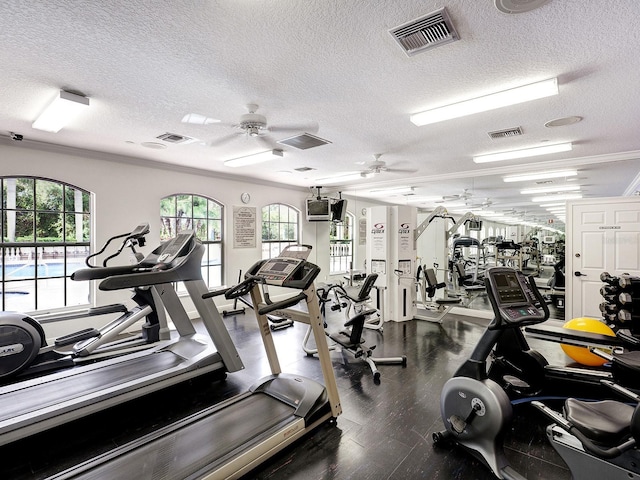 exercise room featuring ceiling fan, a textured ceiling, wood-type flooring, and a healthy amount of sunlight