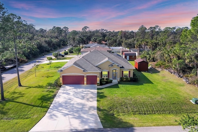 view of front of property featuring driveway, a shingled roof, an attached garage, a front lawn, and stucco siding