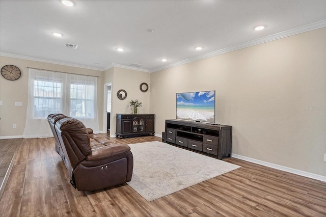 living area with ornamental molding, wood finished floors, visible vents, and baseboards