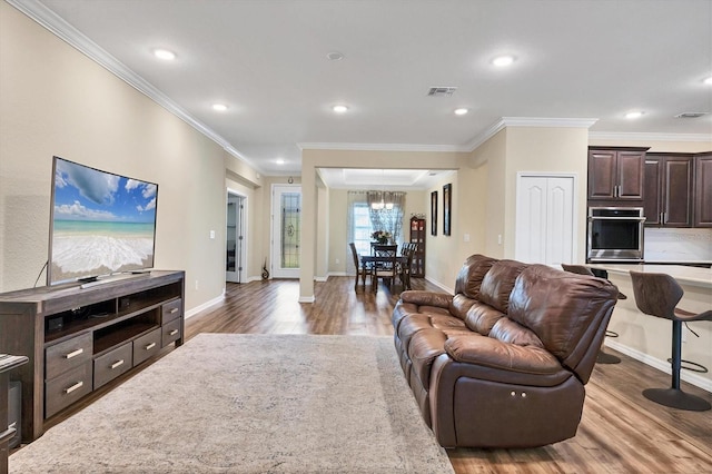 living room with crown molding, visible vents, and wood finished floors