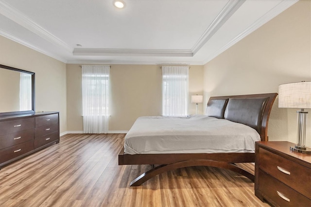 bedroom with baseboards, light wood finished floors, a raised ceiling, and crown molding