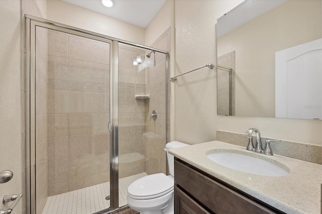 bathroom featuring a shower stall, toilet, and vanity