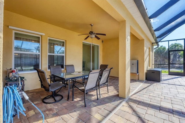 view of patio / terrace with ceiling fan, glass enclosure, and outdoor dining space