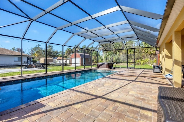 outdoor pool featuring a patio, an outdoor structure, glass enclosure, and a hot tub