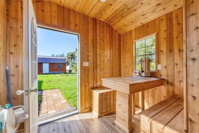 doorway with lofted ceiling, wood ceiling, wooden walls, and wood finished floors