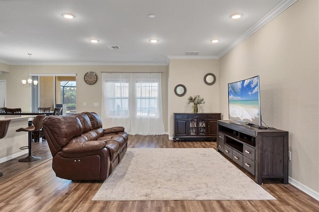 living room featuring ornamental molding, visible vents, and wood finished floors