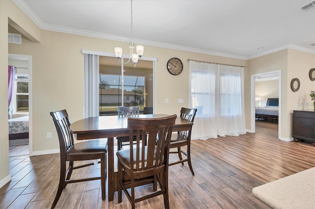 dining area with a notable chandelier, visible vents, wood finished floors, and ornamental molding