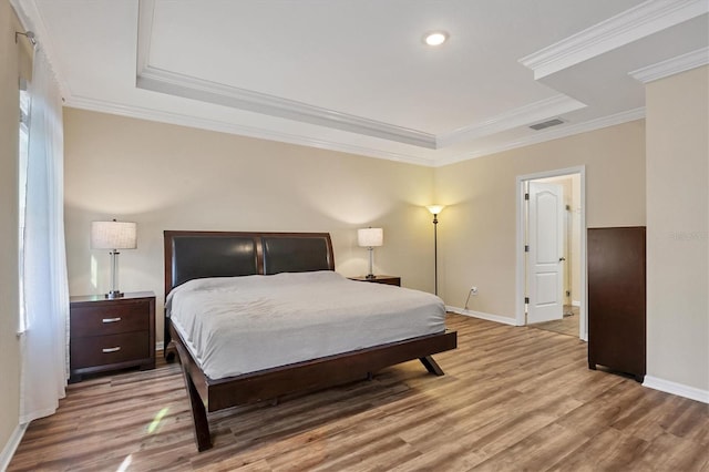 bedroom with baseboards, wood finished floors, visible vents, and crown molding