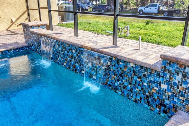 view of swimming pool with glass enclosure and a lawn