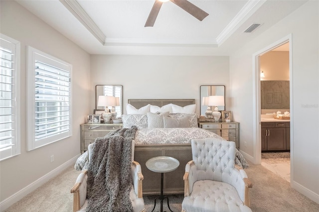 bedroom featuring light carpet, connected bathroom, and a raised ceiling