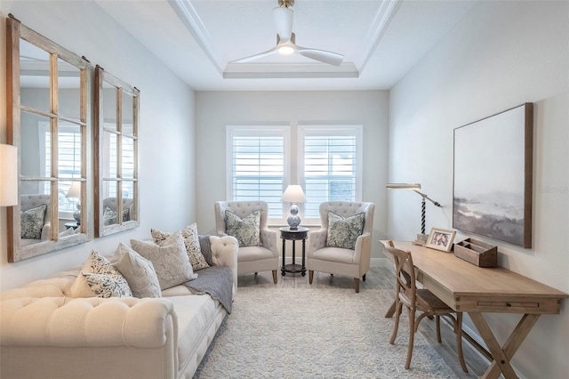 living area with a tray ceiling, ceiling fan, and carpet