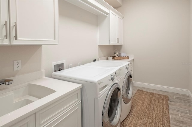 laundry area with cabinets, sink, light hardwood / wood-style flooring, and washing machine and clothes dryer