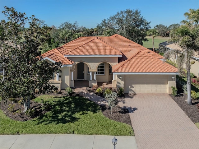 mediterranean / spanish home with a garage and a front lawn