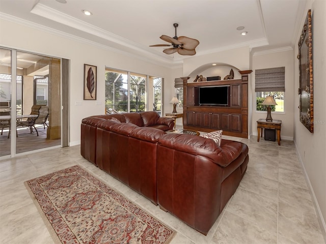 living room featuring ceiling fan, ornamental molding, and a tray ceiling