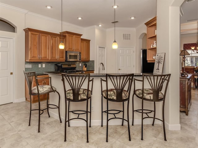 kitchen with stainless steel appliances, crown molding, hanging light fixtures, and a kitchen bar