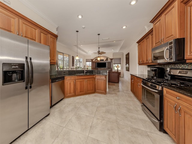 kitchen featuring sink, decorative light fixtures, dark stone counters, ornamental molding, and stainless steel appliances