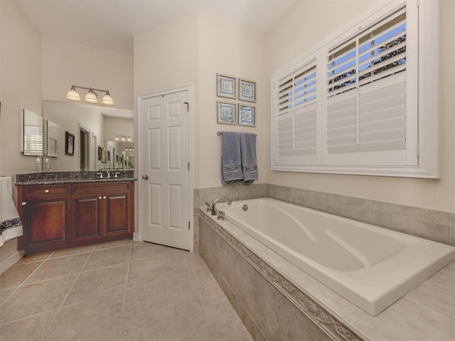 bathroom with a relaxing tiled tub, vanity, and tile patterned floors