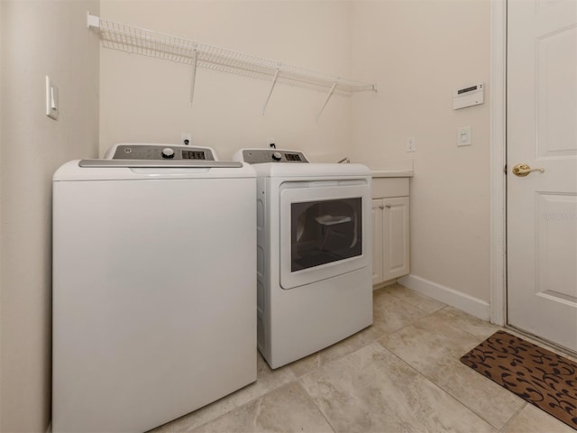 clothes washing area featuring cabinets and washer and dryer