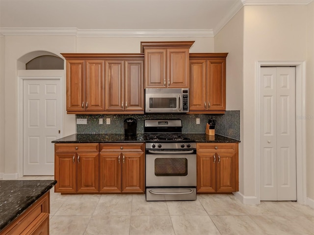 kitchen with ornamental molding, appliances with stainless steel finishes, backsplash, and dark stone counters