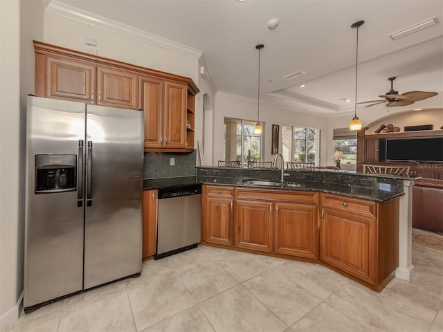 kitchen with sink, hanging light fixtures, stainless steel appliances, ornamental molding, and dark stone counters