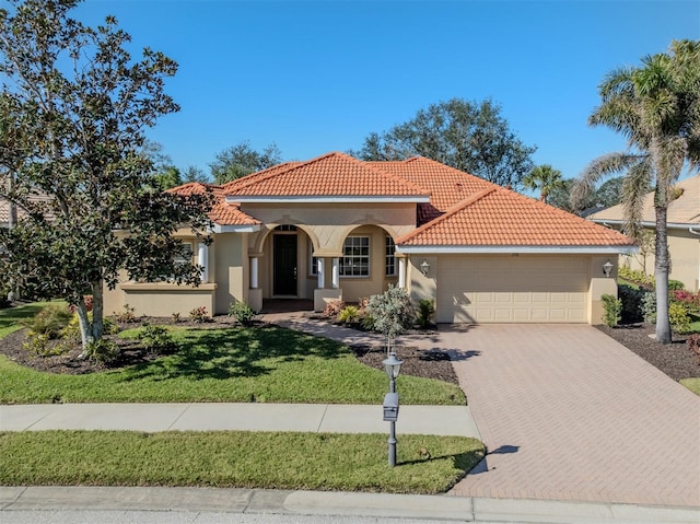 mediterranean / spanish home featuring a garage and a front lawn