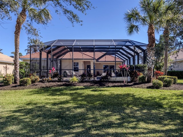 rear view of property featuring a lawn and glass enclosure