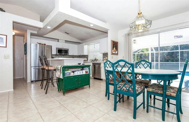 dining area featuring light tile patterned floors and vaulted ceiling