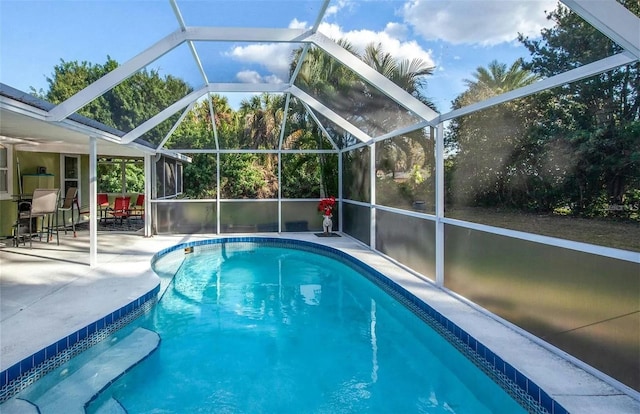 view of swimming pool featuring a patio and a lanai