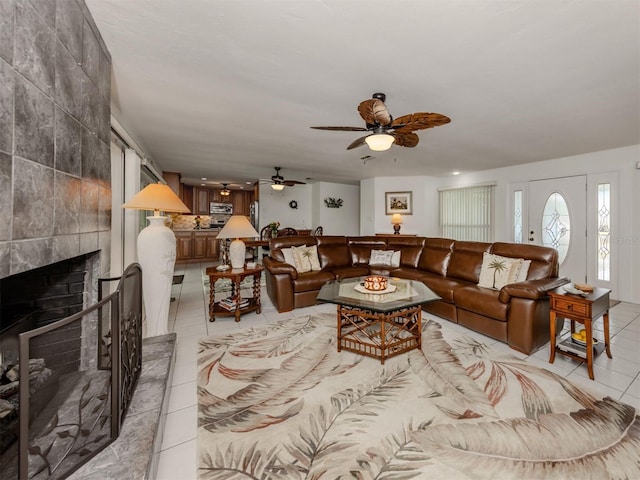 tiled living room with ceiling fan and a fireplace