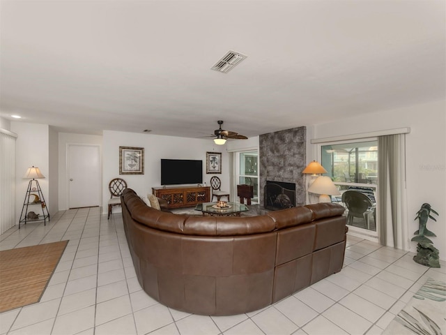 tiled living room with ceiling fan and a fireplace