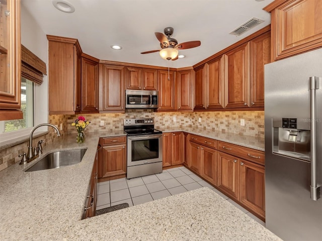 kitchen featuring light stone countertops, appliances with stainless steel finishes, sink, and backsplash