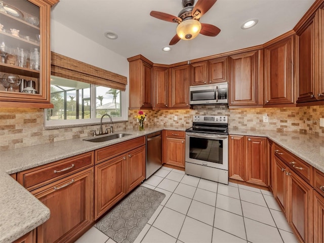 kitchen with light stone counters, sink, light tile patterned floors, and stainless steel appliances