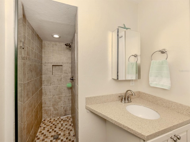 bathroom with vanity and a tile shower