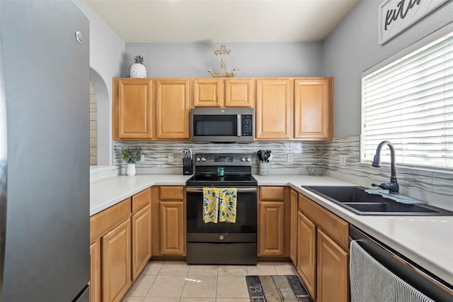 kitchen with light tile patterned flooring, appliances with stainless steel finishes, sink, and backsplash