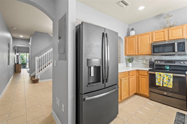 kitchen featuring light brown cabinetry, backsplash, light tile patterned floors, electric panel, and stainless steel appliances