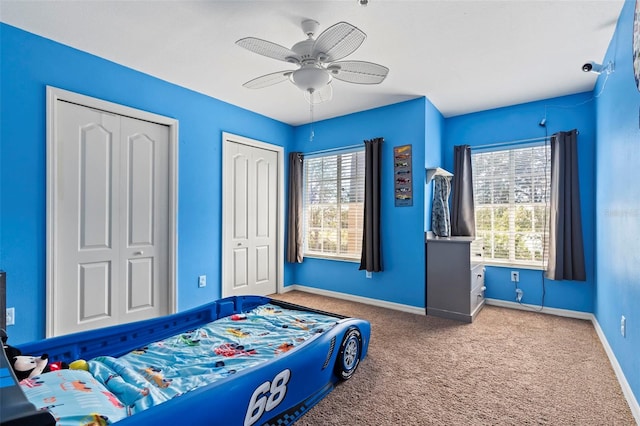 carpeted bedroom featuring multiple closets and ceiling fan