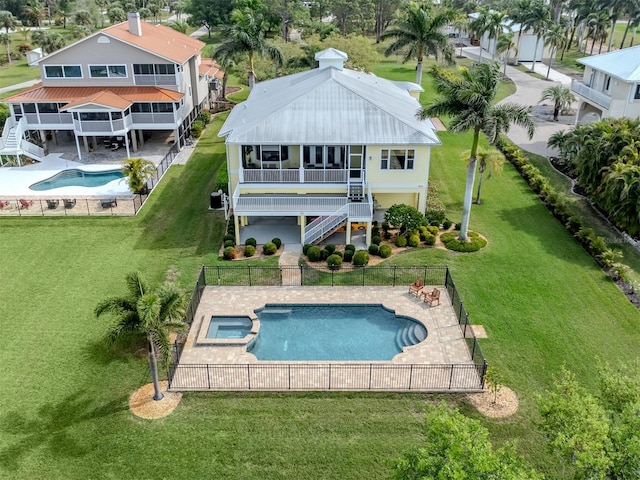 rear view of property with a fenced in pool, a patio area, and a lawn