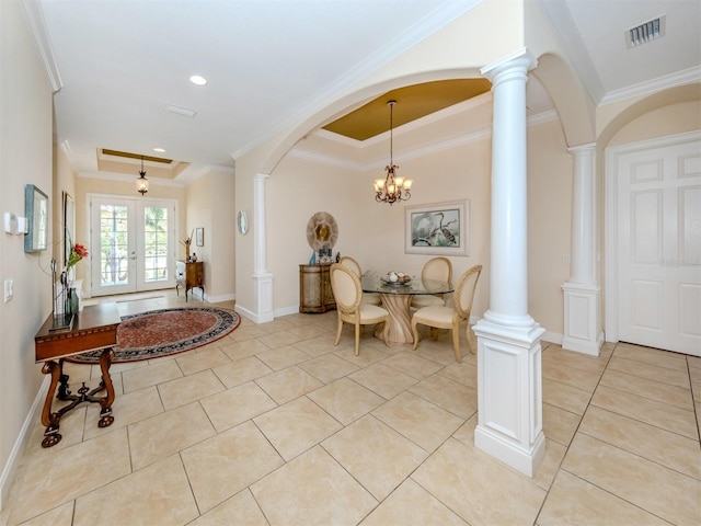 tiled entrance foyer with ornamental molding, decorative columns, and a raised ceiling