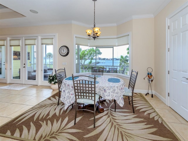 dining area with a water view, ornamental molding, and light tile patterned flooring