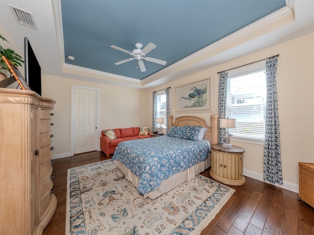 bedroom with dark hardwood / wood-style flooring, crown molding, a raised ceiling, and ceiling fan