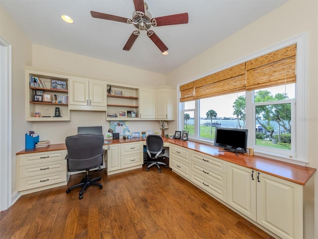 office space featuring built in desk, dark hardwood / wood-style floors, and ceiling fan