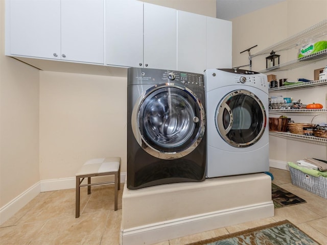 clothes washing area featuring light tile patterned floors, cabinets, and washing machine and clothes dryer