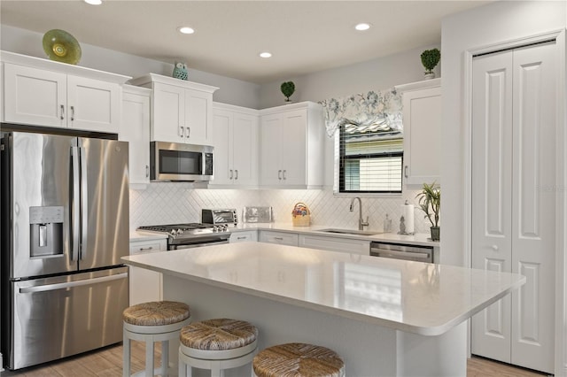 kitchen featuring sink, a breakfast bar area, stainless steel appliances, a center island, and white cabinets