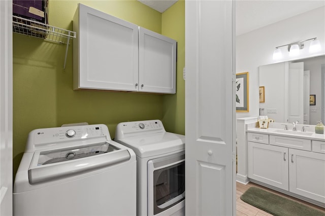 washroom with sink, light hardwood / wood-style flooring, cabinets, and washing machine and clothes dryer