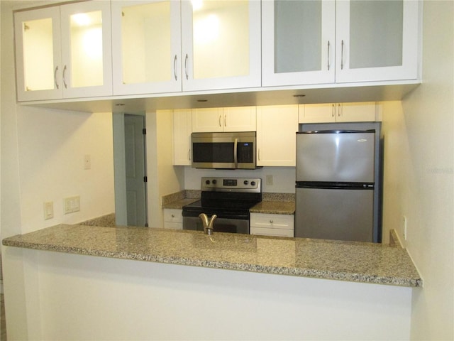 kitchen with light stone countertops, white cabinetry, and appliances with stainless steel finishes