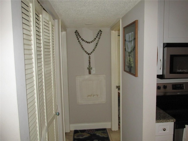 corridor with light tile patterned floors and a textured ceiling