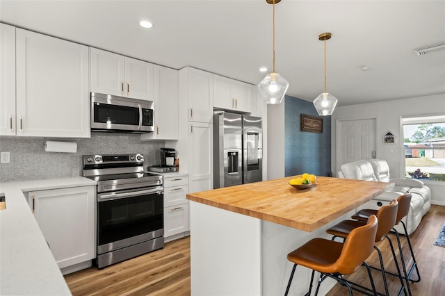 kitchen featuring white cabinetry, a breakfast bar area, stainless steel appliances, and a center island