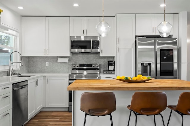 kitchen with white cabinetry, butcher block counters, and appliances with stainless steel finishes