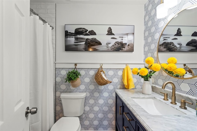 bathroom with vanity, tile walls, and toilet