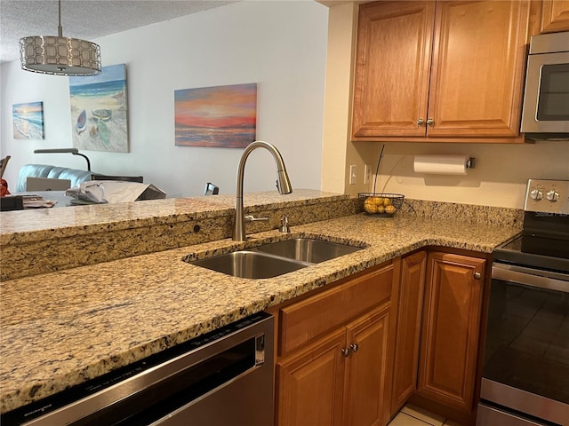 kitchen with pendant lighting, sink, appliances with stainless steel finishes, light stone counters, and a textured ceiling